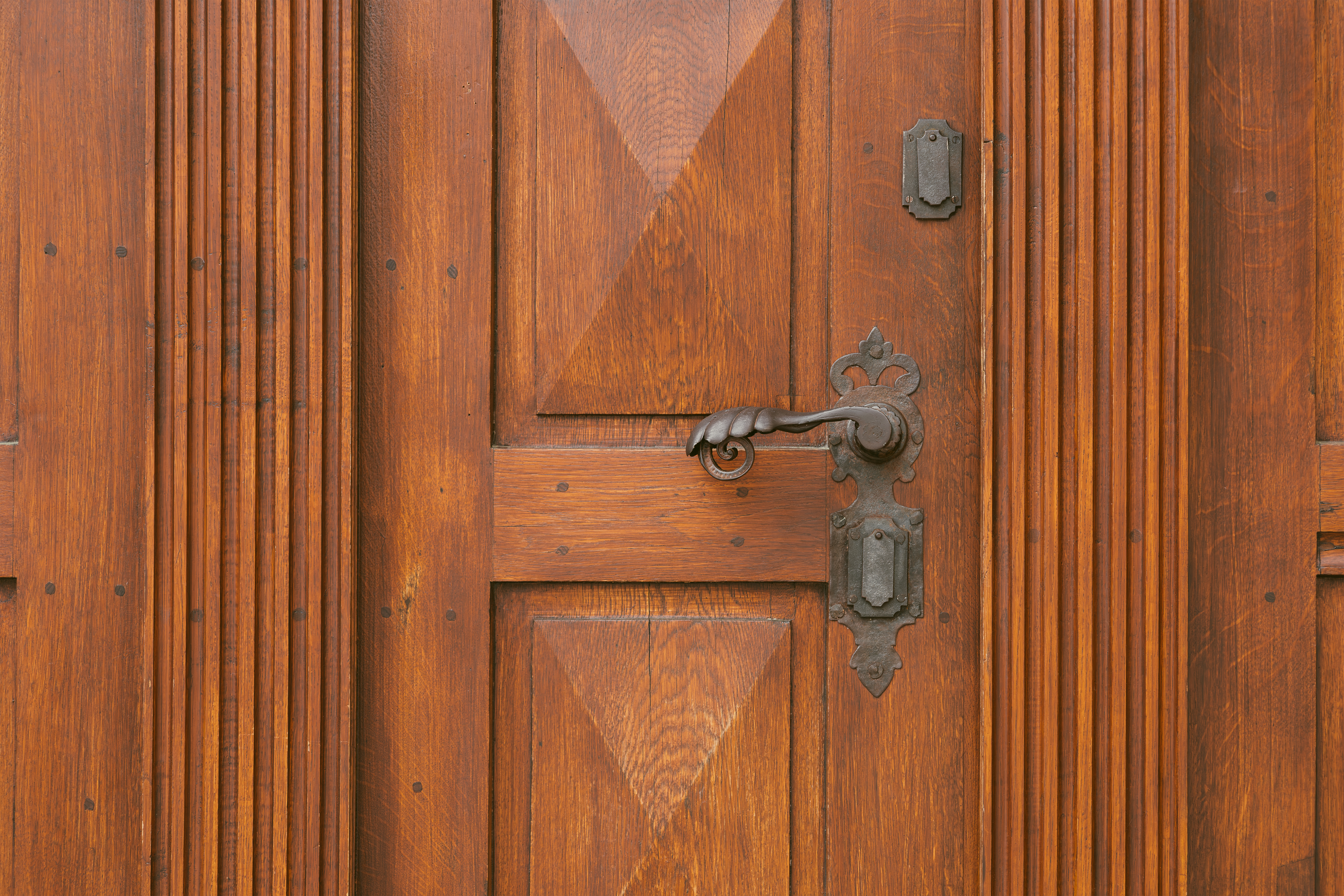 Vintage antique door handle on the old wooden door. Copper keyhole decorative element on weathered brown wood surface. Architecture in Hungary. Details of ornate chocolate colour entrance.