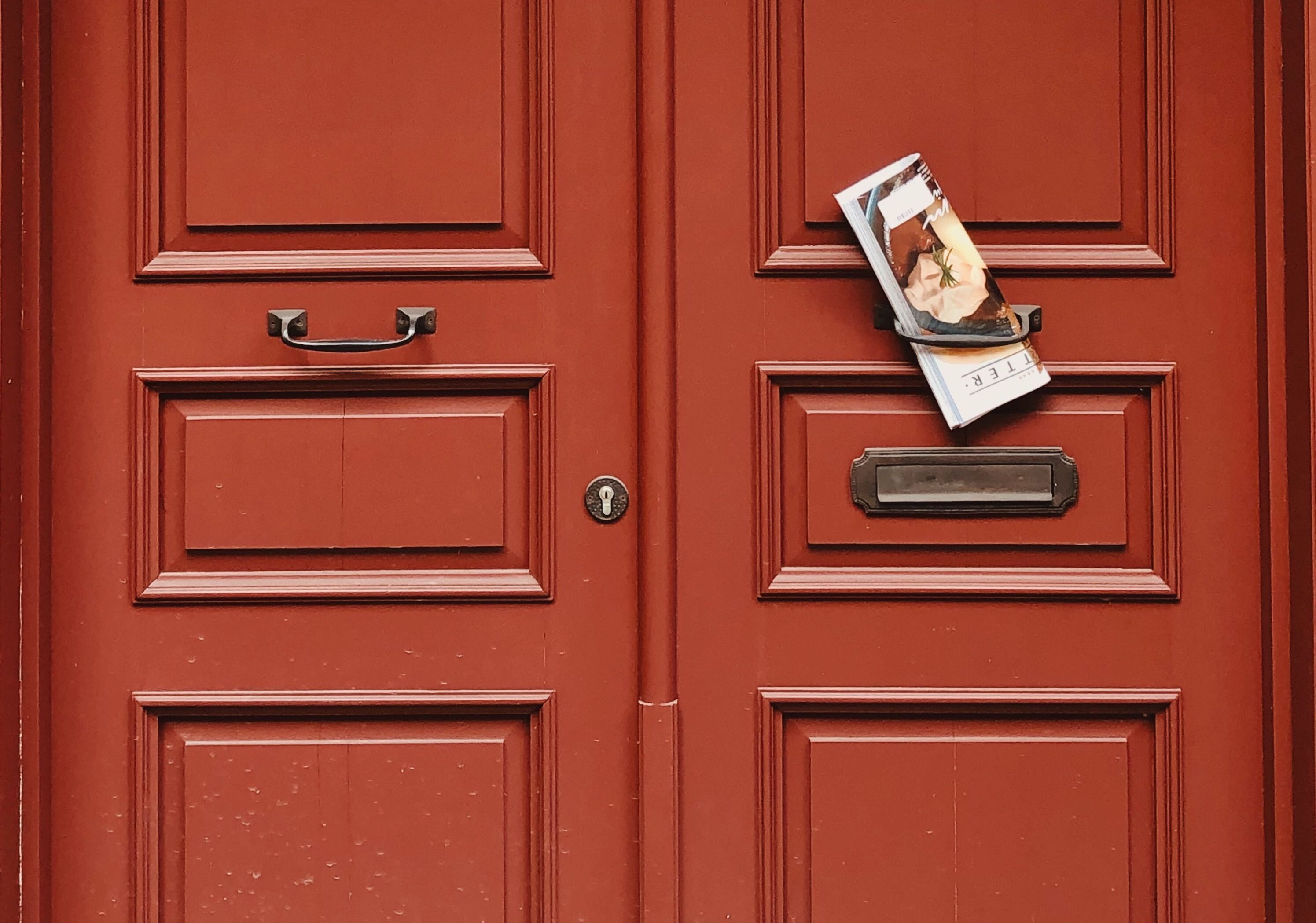 Elegant red wooden door showcasing vintage handles and an exterior magazine slot.