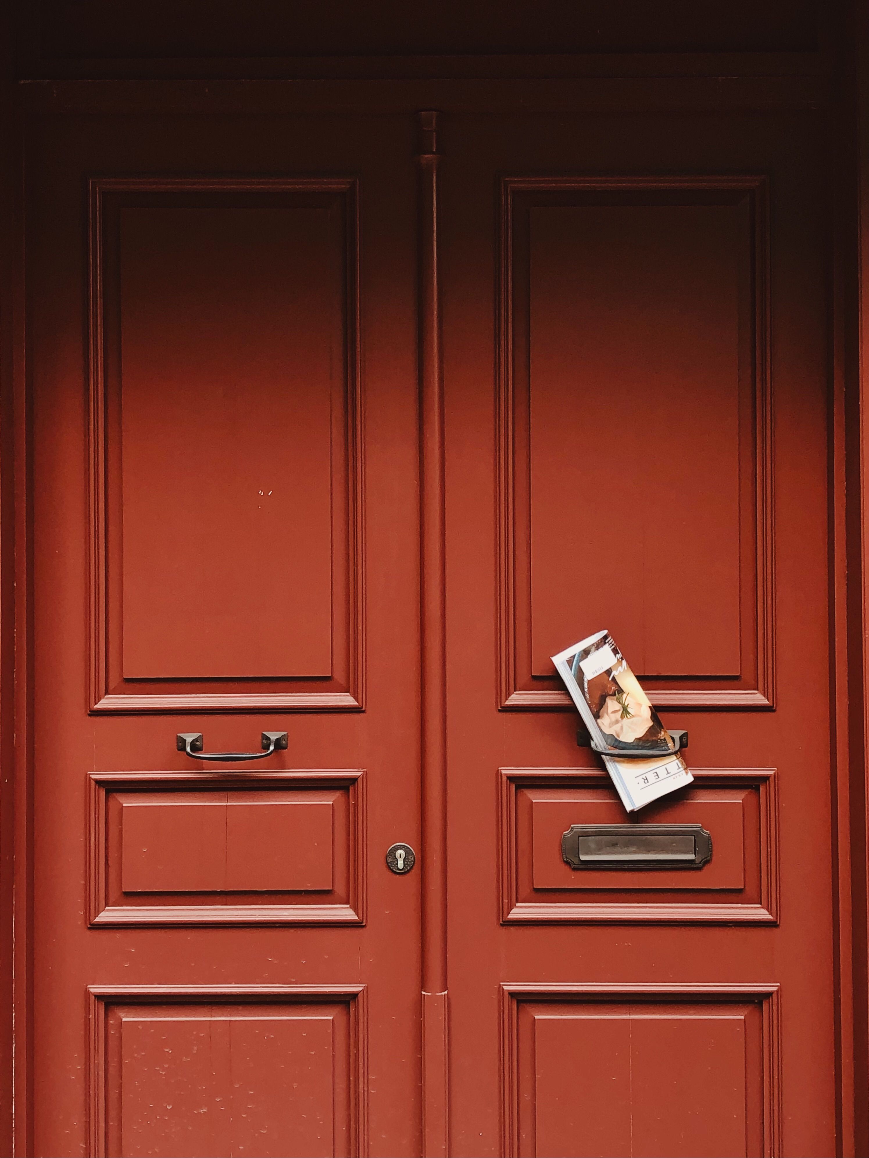 Elegant red wooden door showcasing vintage handles and an exterior magazine slot.