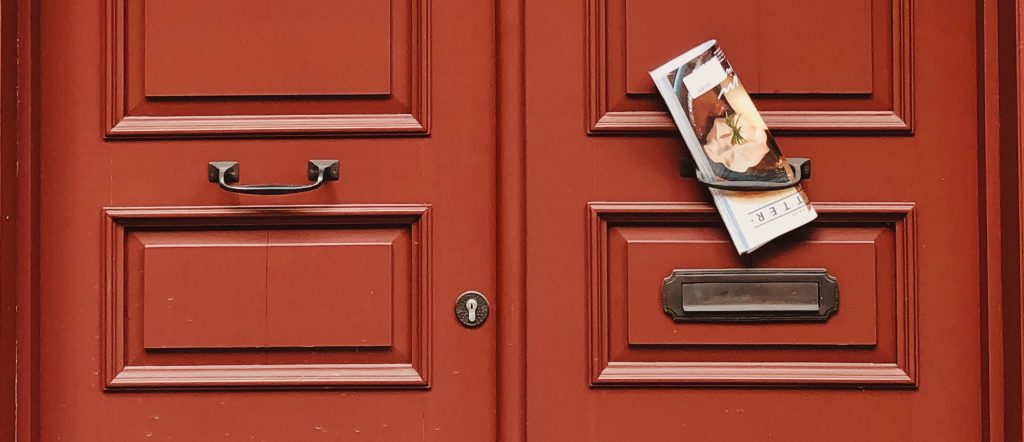 Elegant red wooden door showcasing vintage handles and an exterior magazine slot.